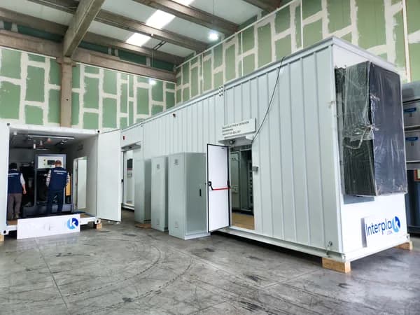 Sala eléctrica modular con puertas abiertas durante el montaje, con letrero de Interplak